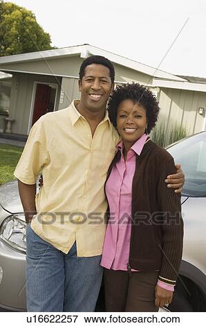 Couple standing by car in front of bungalow View Large Photo Image Stock Photo - Couple standing by car in front of bungalow. Fotosearch