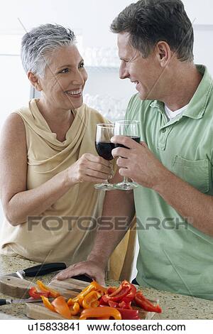 Couple toasting wine in kitchen View Large Photo Image Stock Image - Couple toasting wine in kitchen. Fotosearch