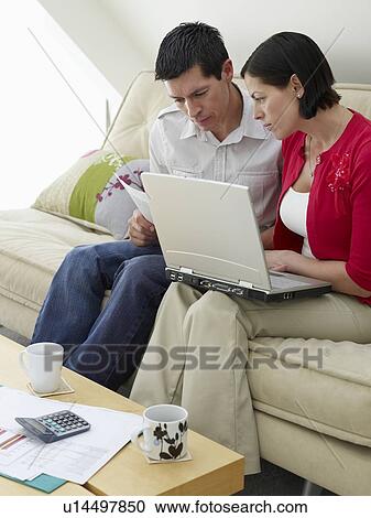 Couple using laptop sitting on sofa View Large Photo Image Stock Image - Couple using laptop sitting on sofa. Fotosearch