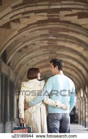 Picture - Couple with arms round each other walking through archway, back view. Fotosearch