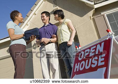 Couple with estate agent outside house put on sale View Large Photo Image Stock Photo - Couple with estate agent outside house put on sale. Fotosearch