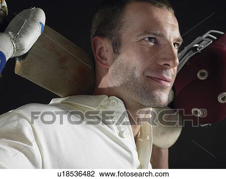 Stock Image - Cricket player holding cricket bat behind shoulders, close-up. Fotosearch