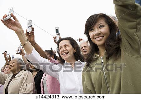 Stock Image - Crowd holding up mobile phones. Fotosearch