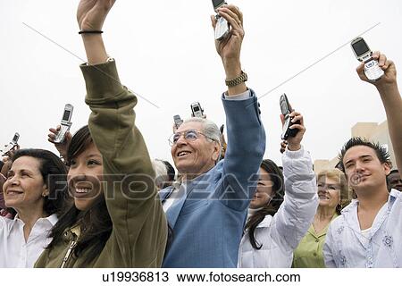 Stock Image - Crowd holding up mobile phones. Fotosearch
