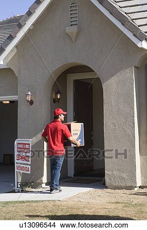 Picture - Delivery man holding Cardboard box. Fotosearch