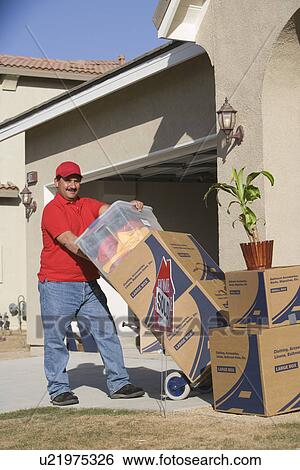 Stock Photograph - Delivery man holding cart with stack of containers. Fotosearch