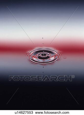 Stock Image - Droplets Hitting Water, causing ripples, close-up. Fotosearch