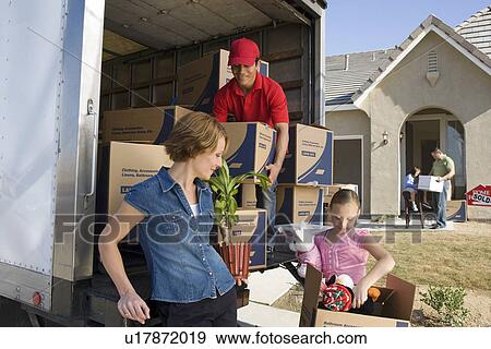 Stock Photo - Family and worker unloading truck of cardboard boxes. Fotosearch
