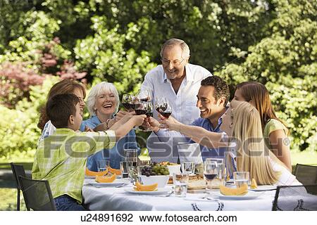 Family toasting at lunch table in back yard View Large Photo Image Stock Image - Family toasting at lunch table in back yard. Fotosearch