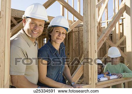 Stock Image - Family with two children (6-9) at construction site, portrait. Fotosearch