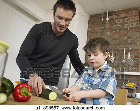 Stock Photo - Father and son (3-4) preparing food in kitchen. Fotosearch