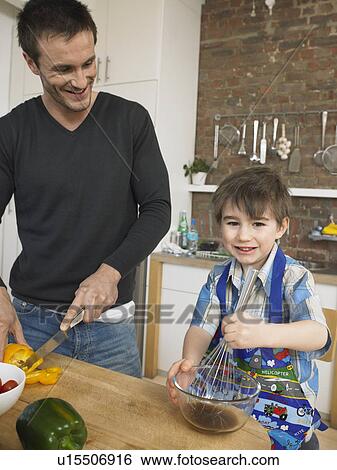 Stock Photograph - Father and son (3-4) preparing food in kitchen. Fotosearch