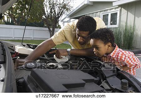 Stock Photo - Father and son (5-6) repairing car's engine. Fotosearch