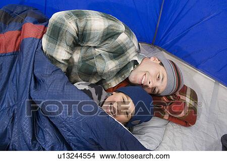 Picture - Father and son lying in tent. Fotosearch