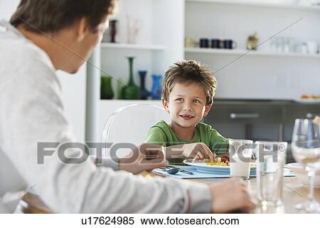 Father and son sitting at table eating pasta View Large Photo Image Stock Photography - Father and son sitting at table eating pasta. Fotosearch