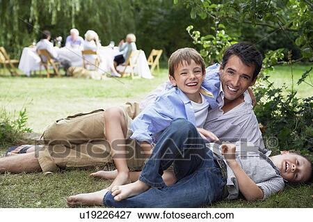 Father and two sons (7-10) having fun on grass in garden View Large Photo Image Stock Photo - Father and two sons (7-10) having fun on grass in garden. Fotosearch