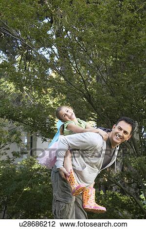 Father giving daughter piggy back ride in park View Large Photo Image Stock Image - Father giving daughter piggy back ride in park. Fotosearch