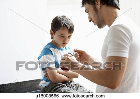 Stock Photograph - Father Giving Son Cough Syrup. Fotosearch
