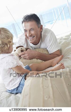 Stock Photography - Father lying on bed Playing with Son. Fotosearch