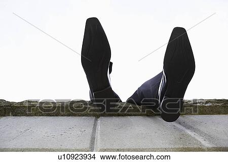 Picture - Feet dangling over wall, low angle view. Fotosearch