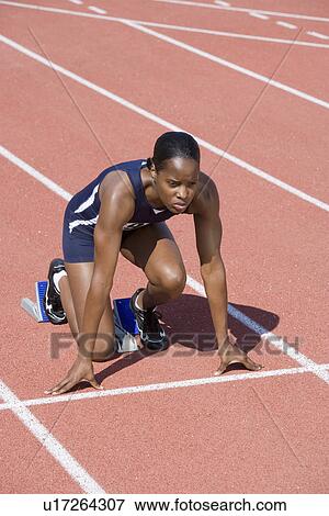 Stock Photo - Female athlete in starting block, ready to run. Fotosearch