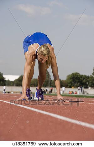 Stock Photo - Female athlete in starting block, ready to run. Fotosearch