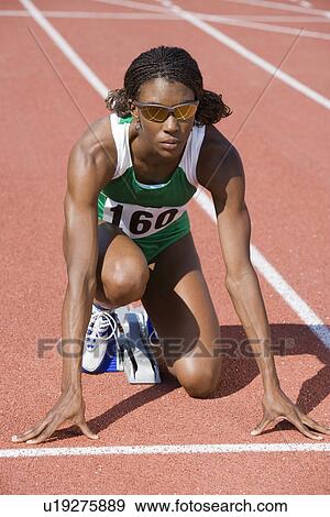 Stock Photo - Female athlete in starting block, ready to run. Fotosearch
