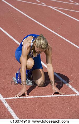 Stock Photograph - Female athlete in starting block, ready to run. Fotosearch