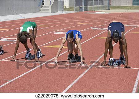 Stock Photo - Female athletes in starting blocks ready to run. Fotosearch
