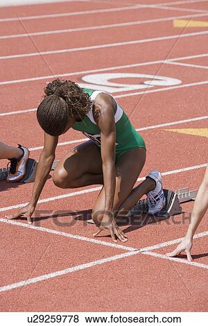 Stock Photo - Female athletes in starting blocks, ready to run. Fotosearch