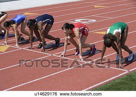 Stock Photograph - Female athletes in starting blocks, ready to run. Fotosearch