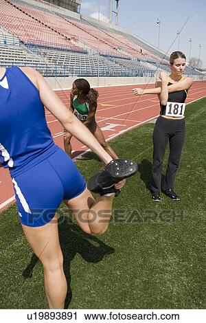 Stock Image - Female athletes warming up for run, low angle view. Fotosearch