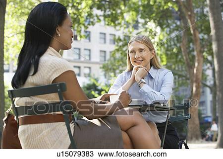 Female colleagues sitting at street cafe View Large Photo Image Stock Image - Female colleagues sitting at street cafe. Fotosearch