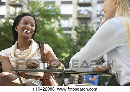 Female colleagues sitting at street cafe View Large Photo Image Stock Photo - Female colleagues sitting at street cafe. Fotosearch