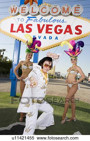 Stock Photography - Female dancers and Elvis impersonator posing in front of Las Vegas welcome sign, Nevada, USA. Fotosearch