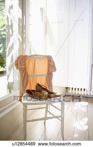 Stock Photo - Female jacket and shoes on chair indoors by window. Fotosearch