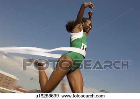 Stock Photo - Female track athlete crossing finishing line. Fotosearch
