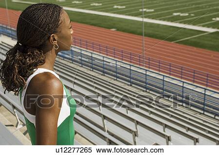 Stock Photography - Female track athlete looking over stadium. Fotosearch