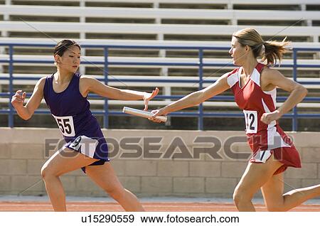 Stock Photo - Female track athlete passing relay baton to another one. Fotosearch