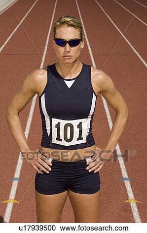 Stock Image - Female track athlete standing on track. Fotosearch