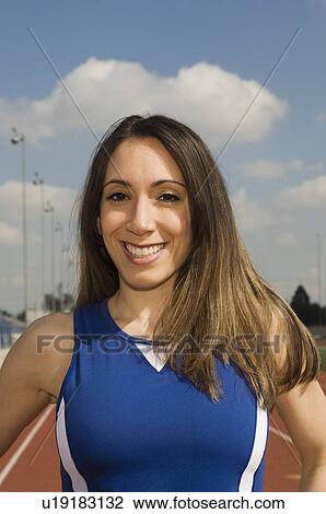 Stock Image - Female track athlete standing on track, portrait. Fotosearch