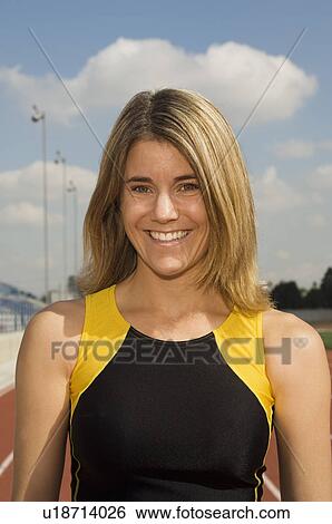 Stock Photograph - Female track athlete standing on track, portrait. Fotosearch