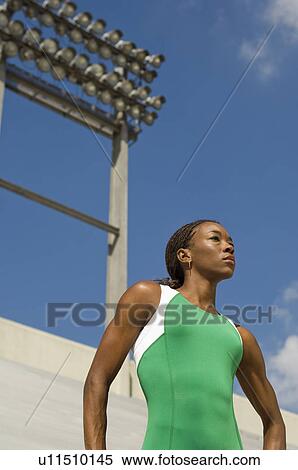 Stock Photography - Female track athlete standing on track. Fotosearch