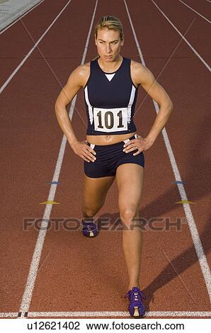 Stock Image - Female track athlete stretching. Fotosearch
