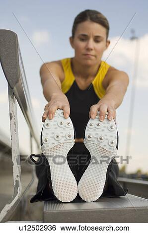 Stock Photograph - Female track athlete stretching. Fotosearch