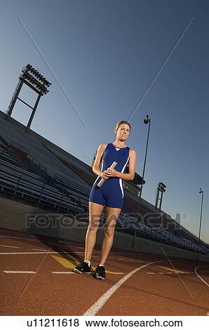 Female track standing on track holding relay baton View Large Photo Image Stock Photo - Female track standing on track holding relay baton. Fotosearch