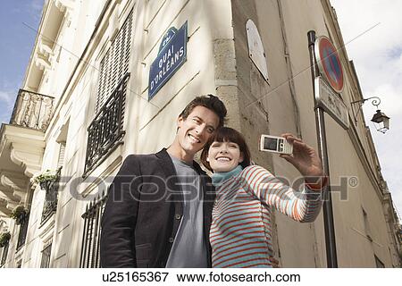 France, Paris, Couple taking self portrait on camera phone in front of apartment block View Large Photo Image Stock Photo - France, Paris, Couple taking self portrait on camera phone in front of apartment block. Fotosearch