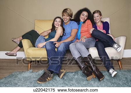 Stock Photography - Friends sitting, arms around one another on sofa. Fotosearch