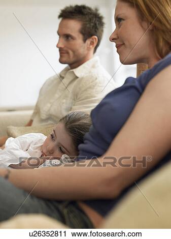 Girl (3-4) watching television with parents on couch View Large Photo Image Stock Image - Girl (3-4) watching television with parents on couch. Fotosearch