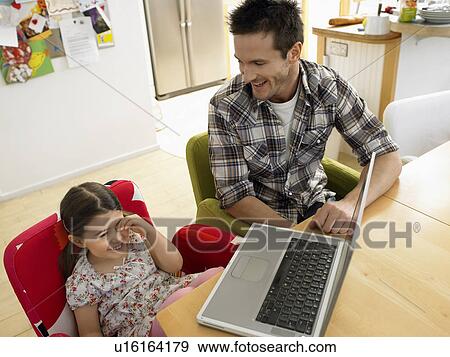 Girl (3-6) using laptop with father in kitchen View Large Photo Image Stock Photo - Girl (3-6) using laptop with father in kitchen. Fotosearch